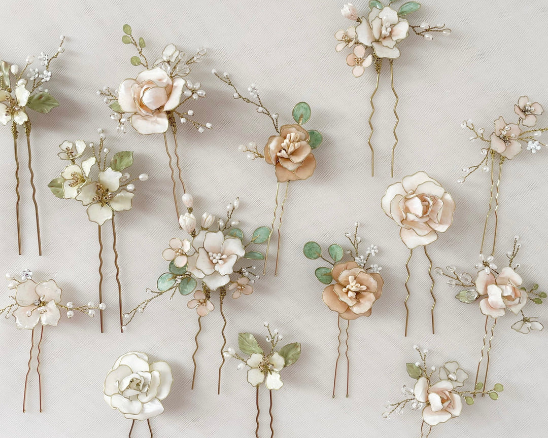 Forcine da sposa con moltitudine di fiori nei toni rosa pastello, corallo, bianco e verde, perfette per acconciature romantiche e colorate.