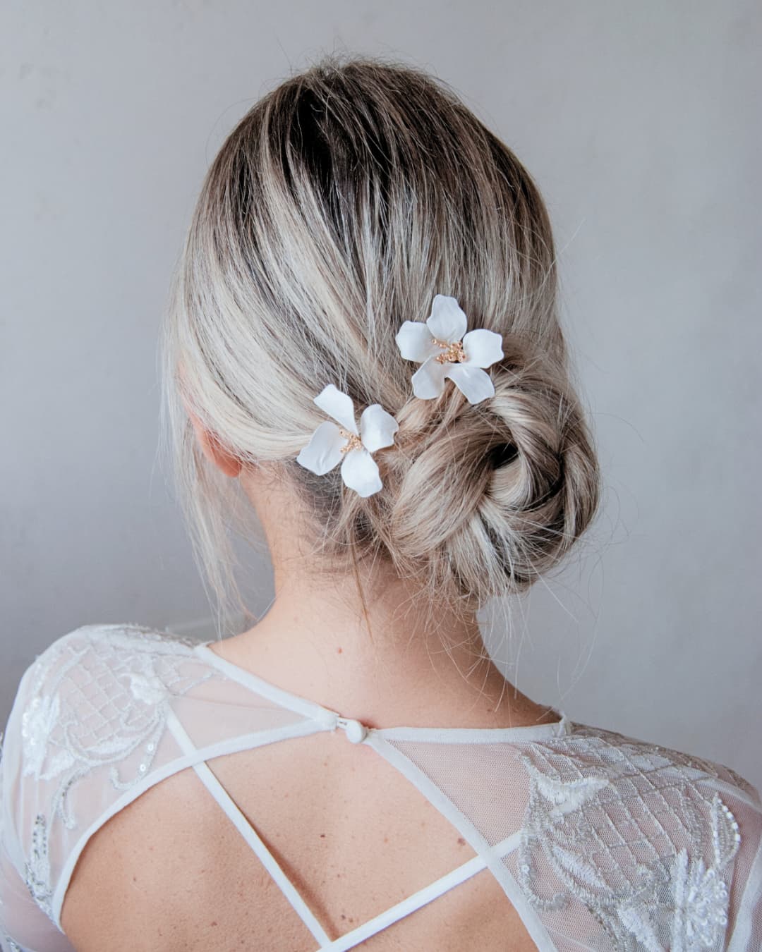 Forcine sposa Magnolia Regalia con fiori bianchi e dettagli oro su sfondo neutro