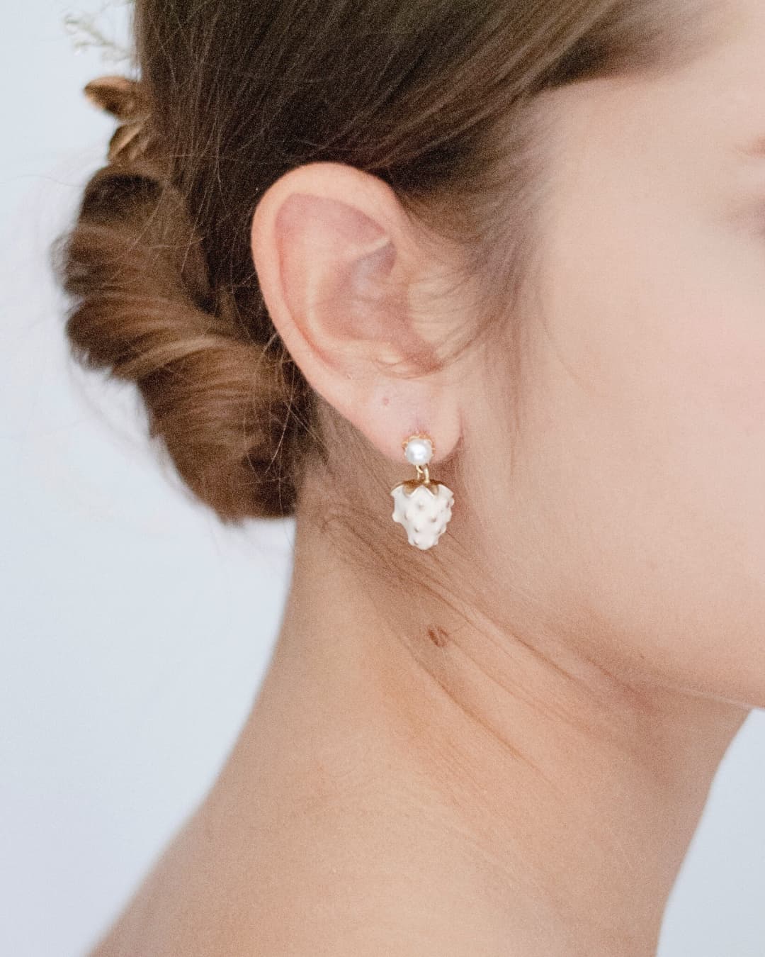 Orecchini pendenti a forma di fragolina Elibre con perla superiore e dettagli dorati indossati da una damigella.
