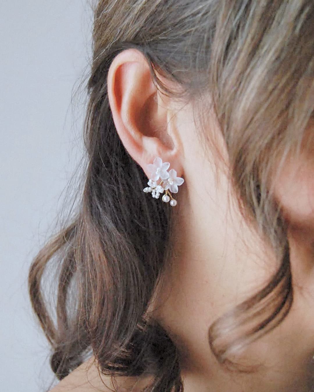 Orecchini sposa Frangipane Elibre con petali bianchi effetto seta e grappoli di perline minuziose.