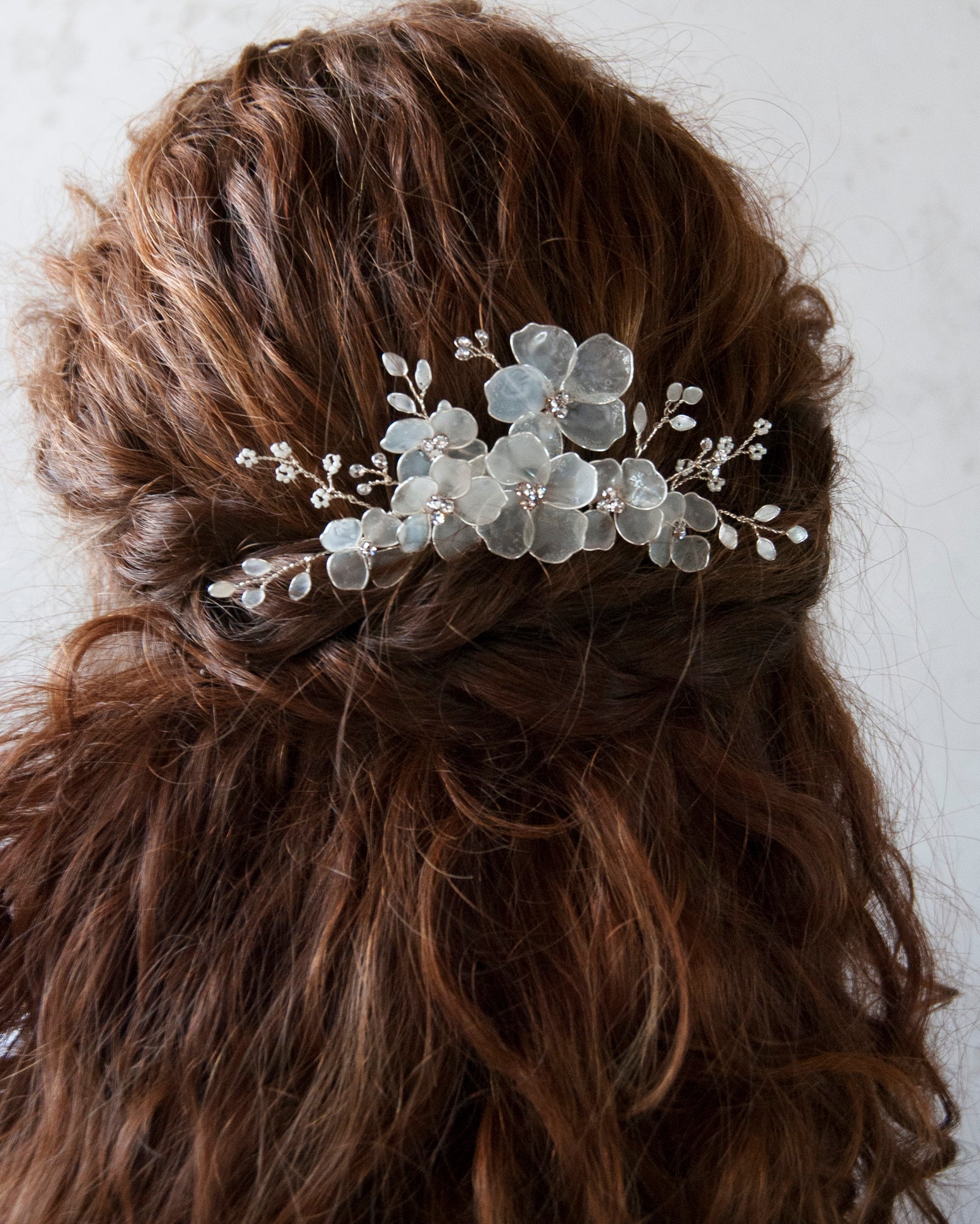 Fiori satinati su pettinino, ideale per un look da sposa elegante e luminoso.