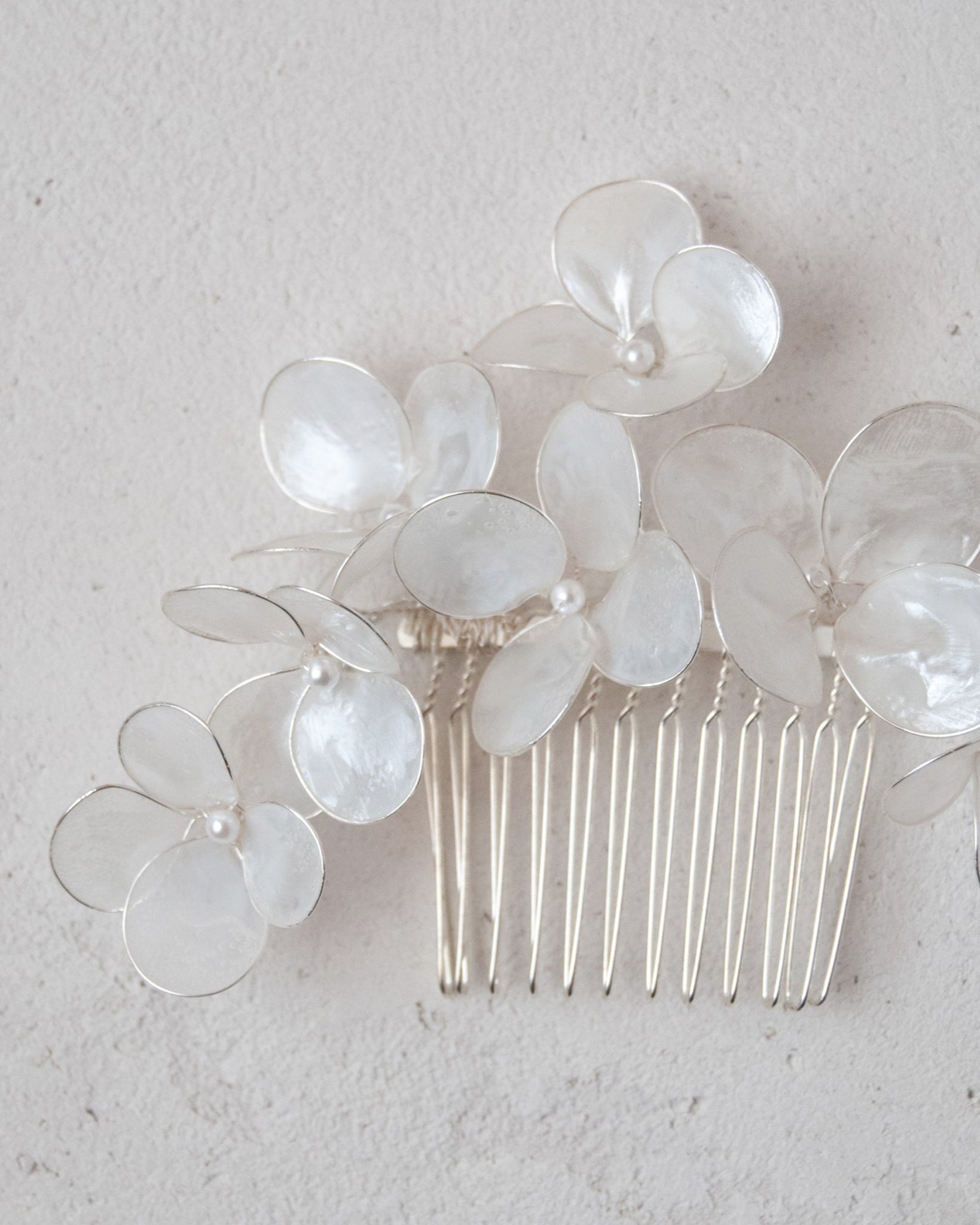 Pettinino floreale con fiori madreperlati, il complemento perfetto per un'acconciatura da sposa chic.