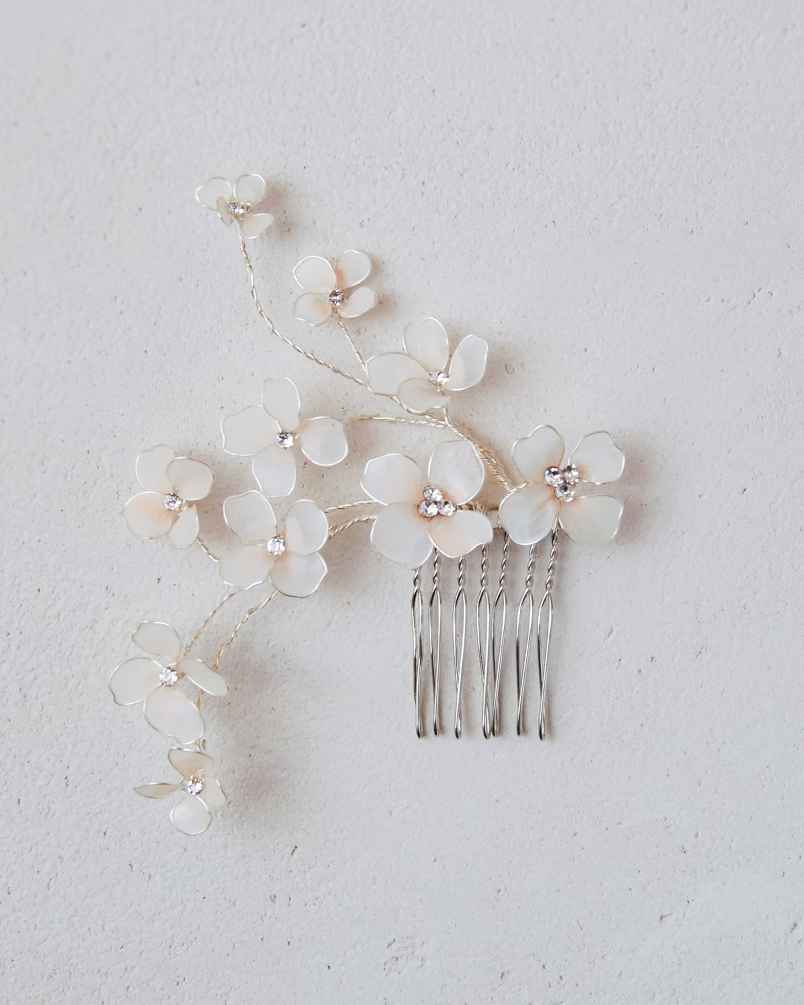 Elegante pettinino floreale con fiori rosa e rami, perfetto per matrimoni raffinati.