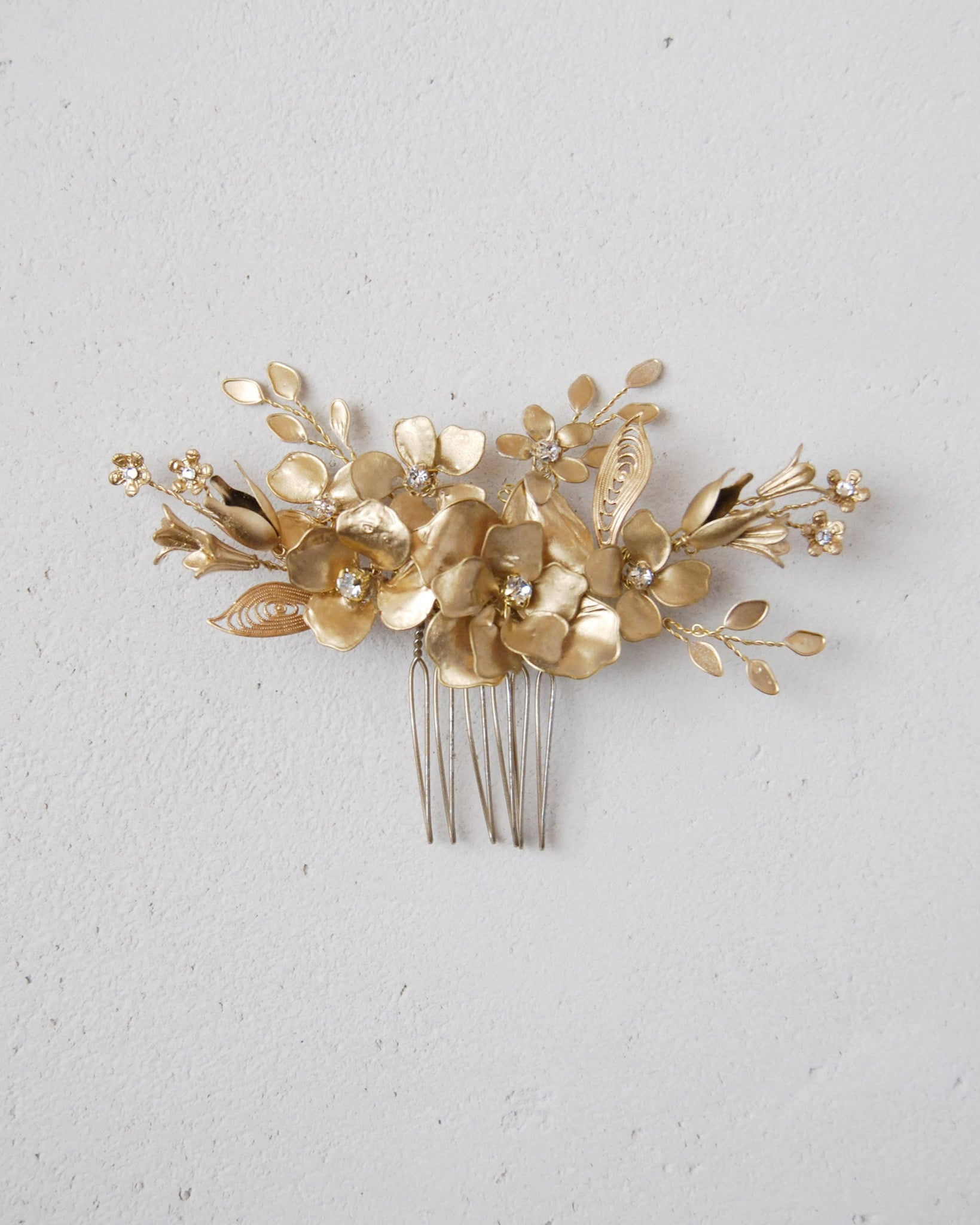 Pettinino floreale in oro, un accessorio di classe per acconciature da sposa eleganti.