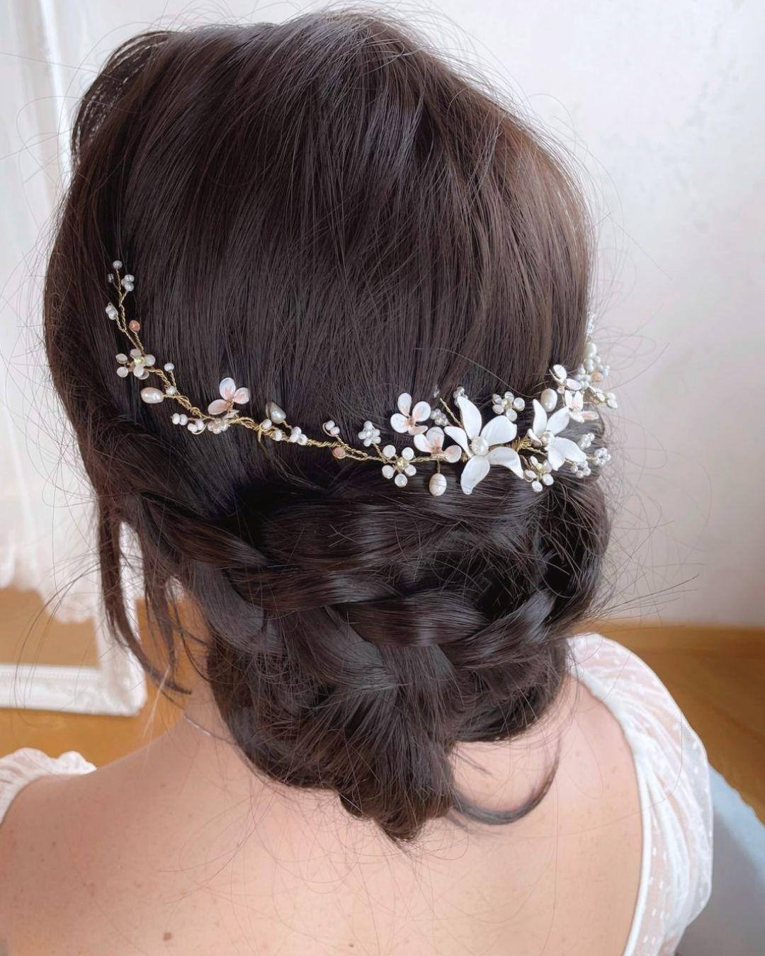 Acconciatura sposa raccolta con il gioiello per capelli Neroli intrecciato tra le onde, stile romantico e botanico.
