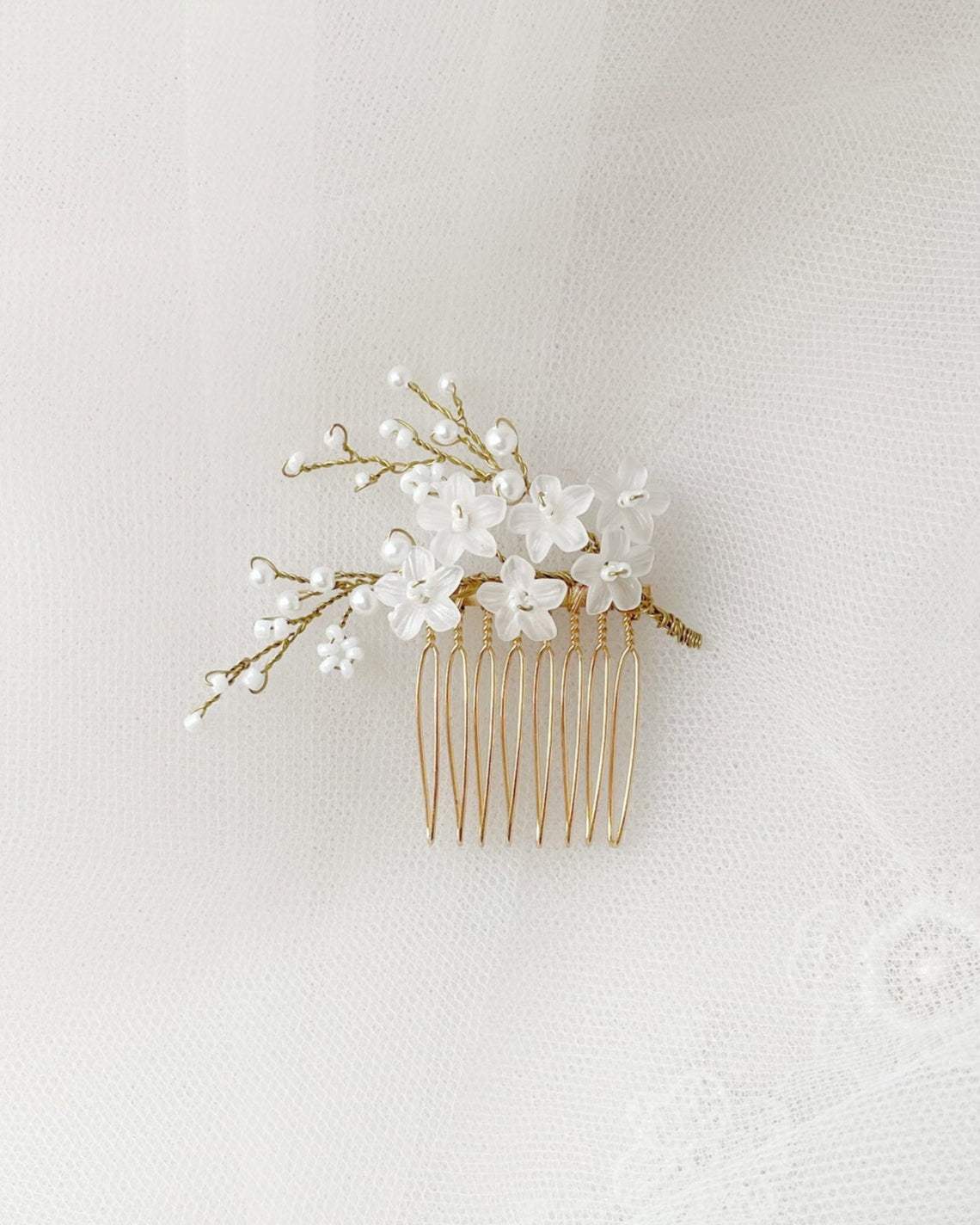 Accessorio da sposa con fiori bianchi e perle, ideale per raccolti raffinati e armoniosi.